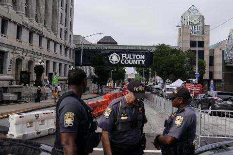 Authorities stand near barricades at the Fulton County courthouse Monday in Atlanta. The sheriff’s office is implementing various security measures ahead of a possible indictment against former President Donald Trump. (BRYNN ANDERSON/Associated Press)