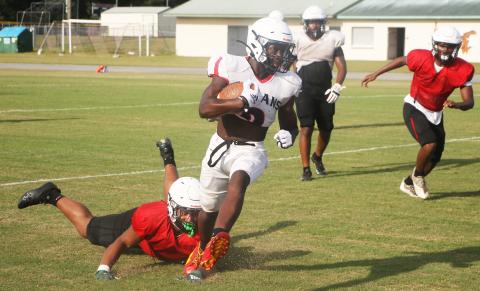 Fort White running back Dakota Fisher runs past linebacker Lecosta Byrd during Friday’s scrimmage. (MORGAN MCMULLEN/Lake City Reporter)