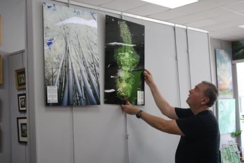 Hugo Cruz hangs some of his infrared photographs up at the Gateway Art Gallery. Cruz is the Gallery’s featured artist for August. (TONY BRITT/Lake City Reporter)