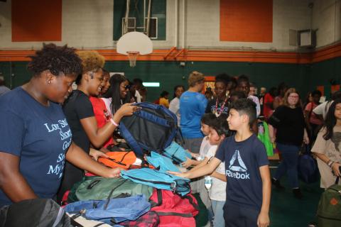 Volunteers hand out backpacks to children Sunday at the Community Barbers Giving Back To The Community Back-To-School event at Richardson Community Center. (TONY BRITT/Lake City Reporter)