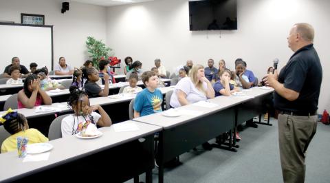 Lake City Police Chief Gerald Butler speaks to a group of more than 35 children on Friday afternoon about the importance of staying in school. (TONY BRITT/Lake City Reporter)