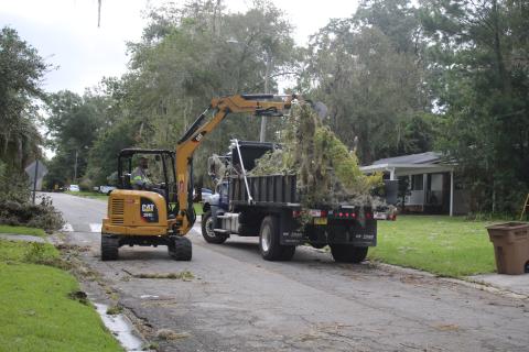 A public works employee with the City of Lake City, loads storm debris into a dump truck on Friday. (TONY BRITT/Lake City Reporter)