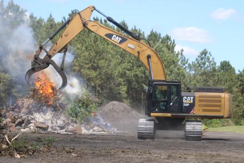 An operator dumps additional debris onto a fire at the Columbia County Public Works department in Lake City. The county also has a site in Fort White open to clear debris following Hurricane Idalia. (TONY BRITT/Lake City Reporter)