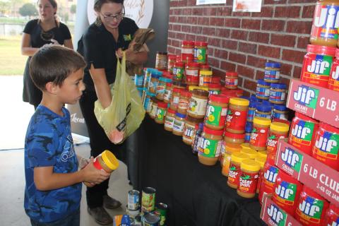 Paul Westridge, 7, helps Adrienne Metcalf align jars of peanut butter that were donated during the second Farm to Table event. The event, which honors Columbia County’s agricultural history, took place Thursday evening at Darby Pavilion. (TONY BRITT/Lake City Reporter)