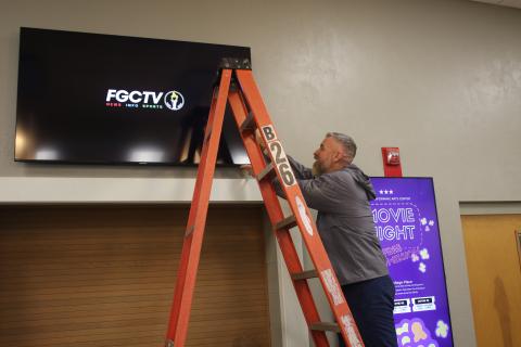 Florida Gateway College Marketing Director Rob Chapman adjusts a television screen in the Levy Performing Arts Center, which is being renovated. (TONY BRITT/Lake City Reporter)