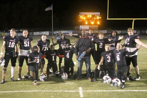 Fort White coach Demetric Jackson and the Indians’ seniors pose with the paddle after beating rival Santa Fe in the ‘Battle for the Paddle’ on Friday night. (MORGAN MCMULLEN/Lake City Reporter)