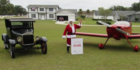 Mark Wiencek dresses as Santa next to a Cessna and a box of presents for Toys for Tots. (TONY BRITT/Lake City Reporter)