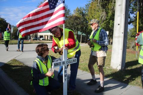 Mia Denney, a Columbia High School JROTC cadet holds an American flag as David Donovan drills it to a cross on Saturday morning. (TONY BRITT/Lake City Reporter)