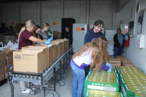 A group of Cambridge Prep Academy students (far left) and Columbia High SGA students add food items to boxes on Thursday morning during the Catholic Charities Thanksgiving Basket Giveaway. More than 559 local families benefited during the effort. (TONY BRITT/Lake City Reporter)