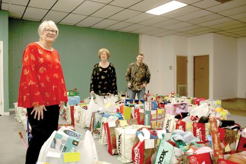 Meally Jenkins (from left), Christmas Dream Machine founder and director, stands amid bags of gifts with volunteers Janet Stanford and Chad Brown on Wednesday afternoon. The Christmas Dream Machine served 616 children this Christmas and was distributing the final bags to families on Wednesday afternoon. (TONY BRITT/Lake City Reporter)