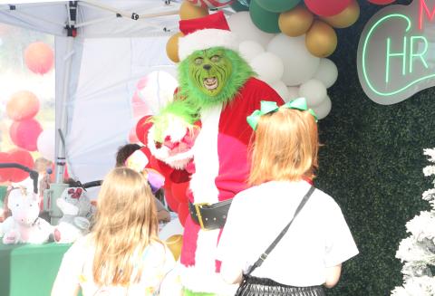 The Grinch reacts to a pair of children approaching him at the City of Lake City’s Holiday Market in downtown Lake City on Saturday. (MORGAN MCMULLEN/Lake City Reporter)