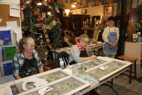 Tina Teasley (from left) and Tami Saperstein paint a snowman on window panes during an art class at the Blue Goose Studio on Thursday afternoon during the Downtown Art Stroll. (TONY BRITT/Lake City Reporter)