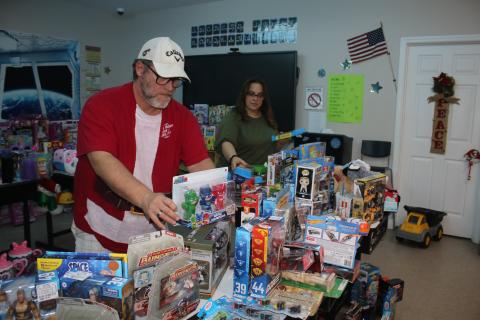 John ‘Lit’ Cole (from left), Kids Feeding Kids president, and Sharon Simpkins set up toys for the Kids Feeding Kids Christmas event. (TONY BRITT/Lake City Reporter)