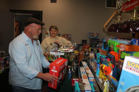 Chris Samson (from left), Exalted Ruler of Lake City Elks Lodge #893, gets help from Brandy Meeks as the two add toys for the Elks Lodge Childrens Christmas Party which will take place Sunday at the building. (TONY BRITT/Lake City Reporter)