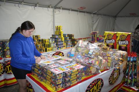 Rorie Lee, a Columbia FFA student, writes a list of prices for the fireworks tent. (TONY BRITT/Lake City Reporter)