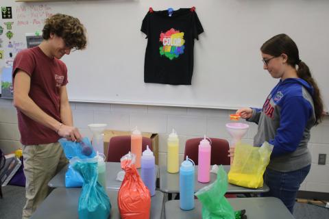 Brody Crews (left) and Isabel Heeke, Fort White High School National Honor Society club officers, fill dispensers with paint for the club’s color fun run that will take place on Saturday at the school’s football stadium. (TONY BRITT/Lake City Reporter)