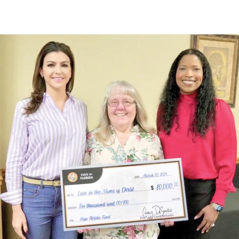 Love INC of Suwannee County Executive Director Martha Wood (center) receives a $10,000 award from First Lady Casey DeSantis and Department of Children and Families Secretary Shevaun Harris on Friday in Live Oak. (COURTESY)