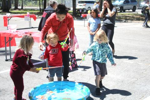 Aniya Woodcock (from left), 4, Khalil Williams, 2, and Parker Pemberton, 4, get help from Katie Stewart as the youngsters play a game attempting to catch plastic fish at the Spring Family Fun Day at Ichetuckee Springs State Park on Saturday. (TONY BRITT/Lake City Reporter)
