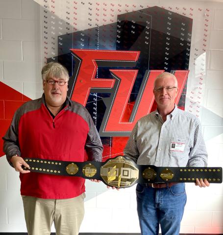 Fort White High School Principal Keith Couey (left) displays the championship belt alongside FDOT District Two Secretary Greg Evans. Fort White students increased their seatbelt wearing by 25% during the course of the competition. (COURTESY)