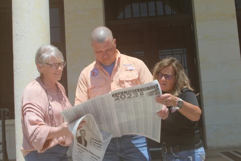 Columbia County Tax Collector’s Office employees La Gina Dow (from left), Thelton Goff and Tracy Nettles look at the county’s delinquent tax rolls Friday as the tax sales certificate auction ended. (JAMIE WACHTER/Lake City Reporter)