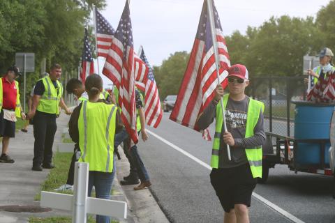 Pheonix Polansky, a cadet with the Columbia High School JROTC program, carries a flag that was later added to a cross for the Flags for Heroes display on State Road 47. (TONY BRITT/Lake City Reporter)