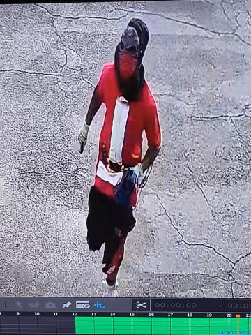 Gary Hollie, wearing a Halloween-style mask and a ‘Santa’ T-shirt, runs from the Dollar General on SW Main Boulevard after an armed robbery at the store on June 12. (COURTESY)