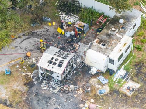 Firefighters sift through debris after a fire consumed an RV camper on State Road 47. (RAY CARPENTER/Special to the Reporter)