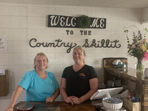 Pam DeLand (left) and assistant manager Stephanie Burgess pose near the entrance to Country Skillit in Lake City. The restaurant just moved to a site across from the Lake City Gateway Airport from Ellisville. (MORGAN MCMULLEN/Lake City Reporter)