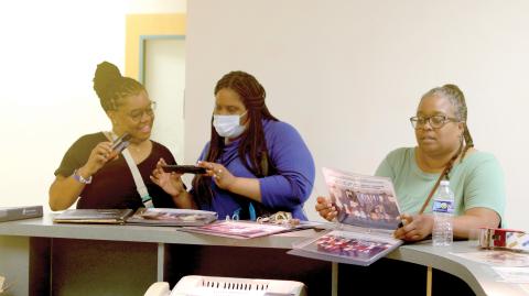 Nakitha Ivery (from left), Violet Wiggins and Nancy James look over old photos from Niblack Elementary on Sunday during a final walkthrough of the school, which is scheduled to be demolished in the near future. The school has served the community for more than 70 years. (TONY BRITT/Lake City Reporter)