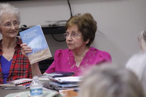 Jonnie Whittington, one of the founders of Writers Ink, holds up one of her books as she talks to the group Monday about not always getting full support in the venture from family members. Writers Ink, a group of authors, meets monthly at the Lafayette County Public Library. Delores Walker, another founder of the group, looks on. (JAMIE WACHTER/Lake City Reporter)
