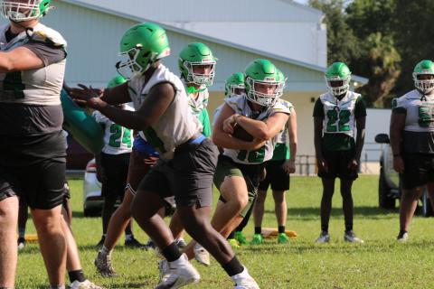 Suwannee running back Clay Starling eyes a hole after taking a handoff from quarterback Thomas Sikes during a drill in the Bulldogs' practice Monday morning. (JAMIE WACHTER/Lake City Reporter)