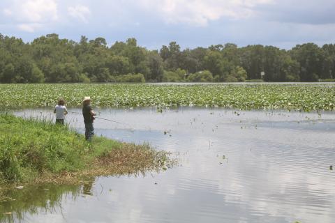 Jamie Spradley (right) and Taylor Kaus, fishing from the banks of Lake Montgomery on Monday, said a new fishing pier would be a nice addition to the lake. (TONY BRITT/Lake City Reporter)