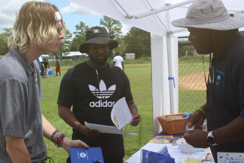 Samuel Jeter (from left) and Carlos Scippio collect information and school materials from Travis George at the Project Cope vendor booth during the inaugural Unity Community Day at Richardson Community Center. (TONY BRITT/Lake City Reporter)