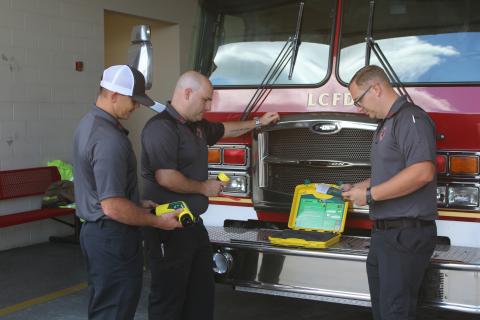 Lake City firefighters Hunter Anderson (from left), Chris Bethea and Gramby Croft look over the department’s new Electric Vehicle Plug Kit and its instruction manual. The newly purchased tool went into service for the department on Monday. (TONY BRITT/Lake City Reporter)