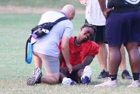 Columbia quarterback Xavier Collins has his knee attended to by the team trainer after being injured at the end of Monday’s practice. (JORDAN KROEGER/Lake City Reporter)