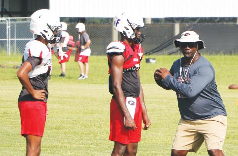 Fort White coach Demetric Jackson (right) works with quarterbacks Gavin Peterson (left) and Jayden Jackson (middle) during practice on Aug. 8. (MORGAN MCMULLEN/Lake City Reporter)