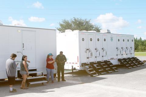 Keith Brown (from left), Sherri Woods and Kate Reeves talk to CCSO Deputy Greg Williams on Sunday while utilizing laundry units in Southside Sports Complex. (TONY BRITT/Lake City Reporter)