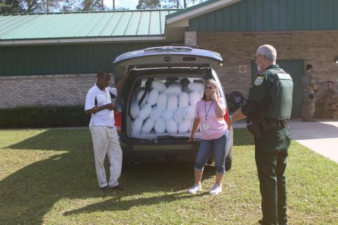Susan Kroh (middle) and Columbia County Sheriff's Deputy Brian Rix (right) attempt to figure out what to do with 1,000 pounds of ice delivered to the Deep Creek Community Center on Sunday afternoon in the back of a Honda Pilot. (TONY BRITT/Lake City Reporter)