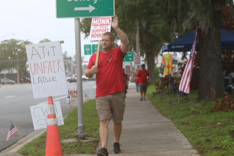 Eric Wilson, an AT&T employee who is on strike, waves at a motorist after the motorist blew their horn for Wilson and the eight other striking employees. (TONY BRITT/Lake City Reporter)