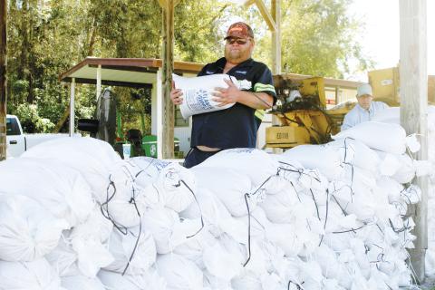 Columbia County Public Works employee Steve ‘Bacon’ Allen carries a sandbag to a pile of bags Tuesday afternoon as the county prepared for the impacts of Tropical Storm Helene, which is expected to make landfall Thursday. (TONY BRITT/Lake City Reporter)