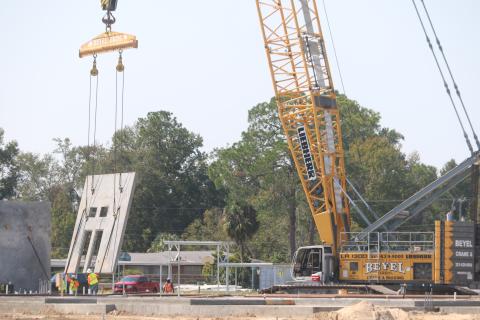 Construction workers help lower a section of one of the walls of the new Niblack Elementary School into position Monday. The walls are being put into place over the next two weeks. (TONY BRITT/Lake City Reporter)