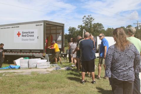 Southern Columbia County residents stand in line to get supplies, including shovels, rakes, tarps, buckets and cleaning supplies, from the American Red Cross in Fort White on Thursday. (TONY BRITT/Lake City Reporter)