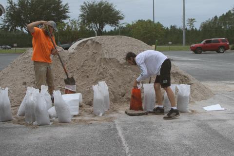 Jasper Webb (from left) and Jonathan Hughes fill sandbags as they prepare for Hurricane Milton. (TONY BRITT/Lake City Reporter)