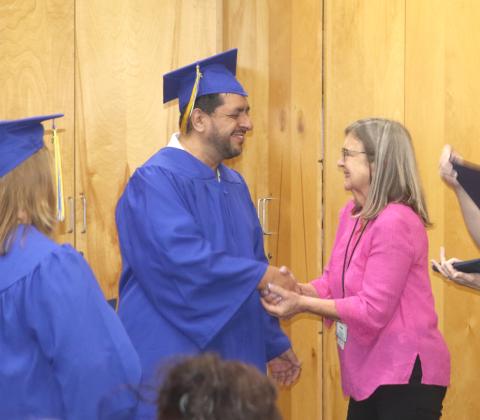 Sergio Miguel Hernandez (from left) is congratulated by Susan Kroh, Columbia County Public Library volunteer and literacy coordinator, as he received his high school diploma in a graduation ceremony on Tuesday night. (TONY BRITT/Lake City Reporter)