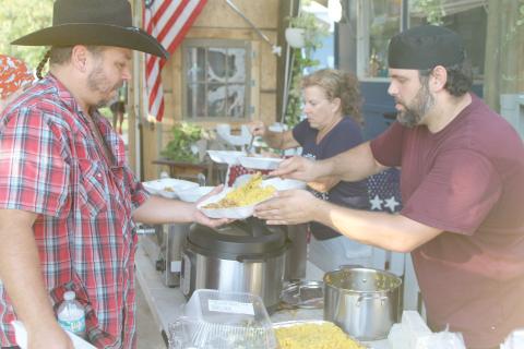 Alexander Veiga, co-owner of The Collective, (right) serves up food during Monday’s event. (TONY BRITT/Lake City Reporter)