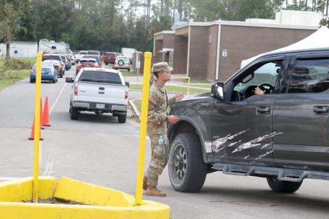 A member of the Florida National Guard helps direct vehicles at a POD (Points of Distribution) site at RIVEROAK Technical College in Live Oak on Saturday. That location has now been moved to the Live Oak Mall at 841 Pinewood Drive SW. (JAMIE WACHTER/Lake City Reporter)