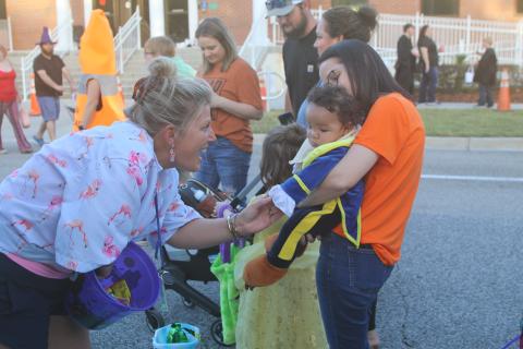 Karri Miles (from left), a DOT employee, interacts with Jaxson Trowell, five months, and his grandmother, Candace Starling, during the DOT’s trunk or treat event on Thursday night. (TONY BRITT/Lake City Reporter)