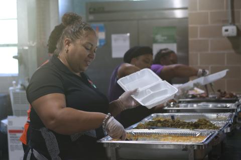 Nicole Callum, a Richardson Community Center board member, serves up macaroni and cheese for a to-go box during the center’s Friends in Need Thanksgiving Dinner on Saturday. (TONY BRITT/Lake City Reporter)