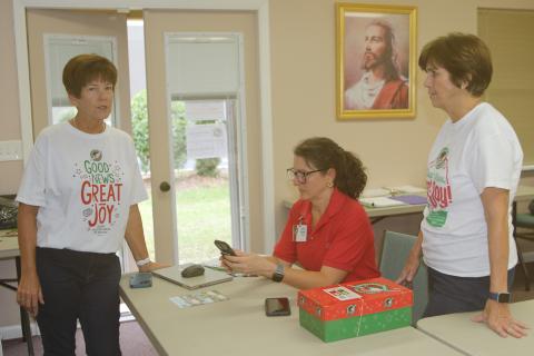 Beth Bullard (from left), Cheri Schultz and Lou Blanton, volunteers at the Operation Christmas Child Shoebox Collection Center in Lake City, work with other volunteers to collect and ship the shoeboxes to Atlanta. (TONY BRITT/Lake City Reporter)