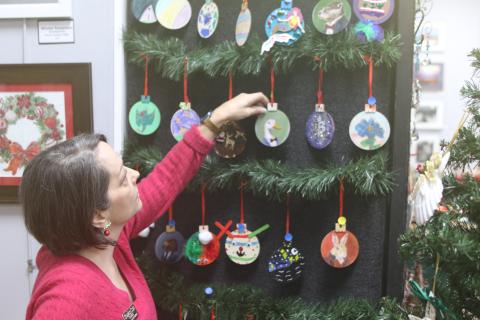 Sheila Carr, Gateway Art Gallery curator, organizes a display of Christmas decorations that are for sale during the organization’s annual Mistletoe Magic fundraiser. (TONY BRITT/Lake City Reporter)